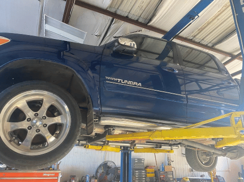 Blue Toyota Tundra truck lifted on hydraulic car lift for undercarriage service and inspection