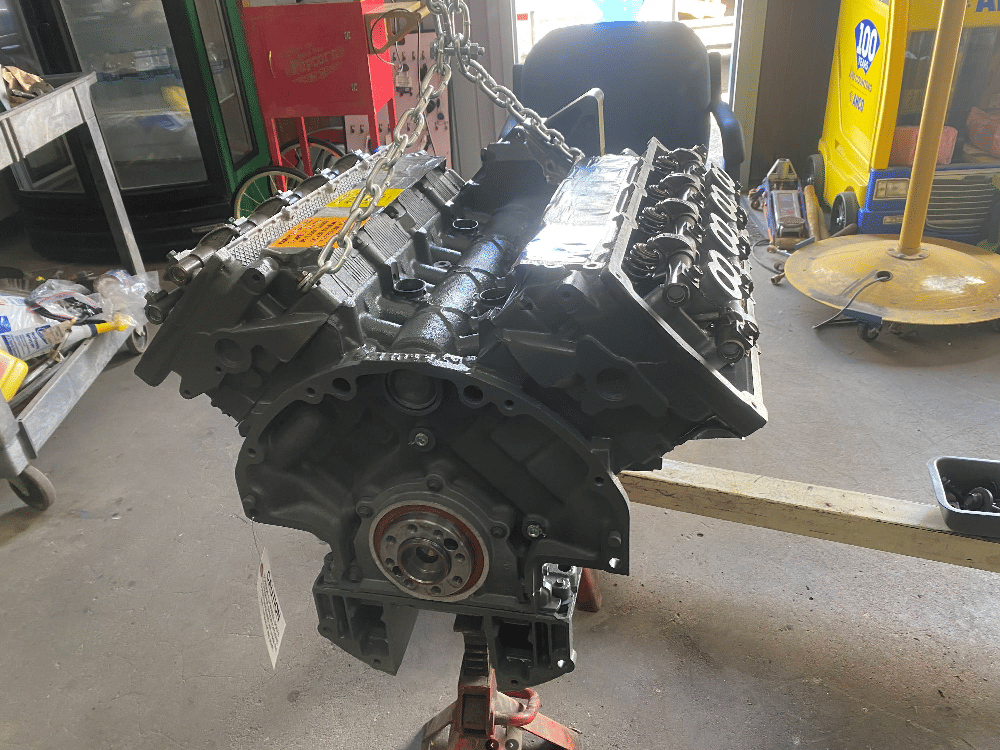 Rebuilt V8 engine suspended on chain hoist ready for installation at RJ Fox Automotive