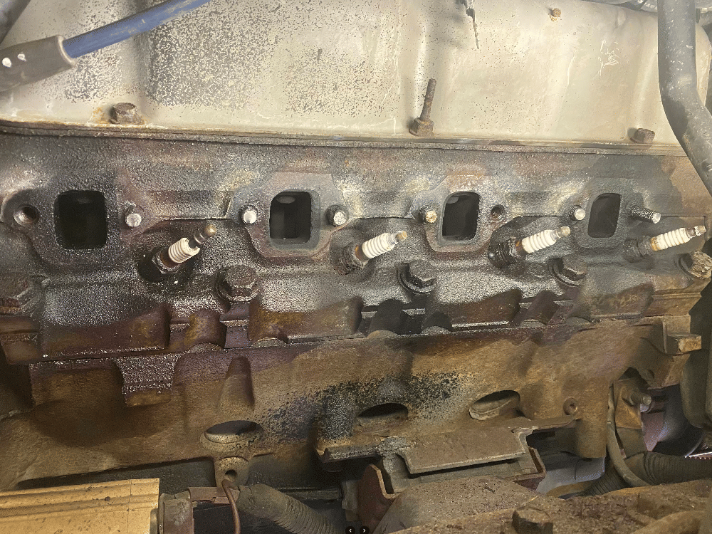 V8 engine block showing intake manifold surface and spark plug wells during rebuild