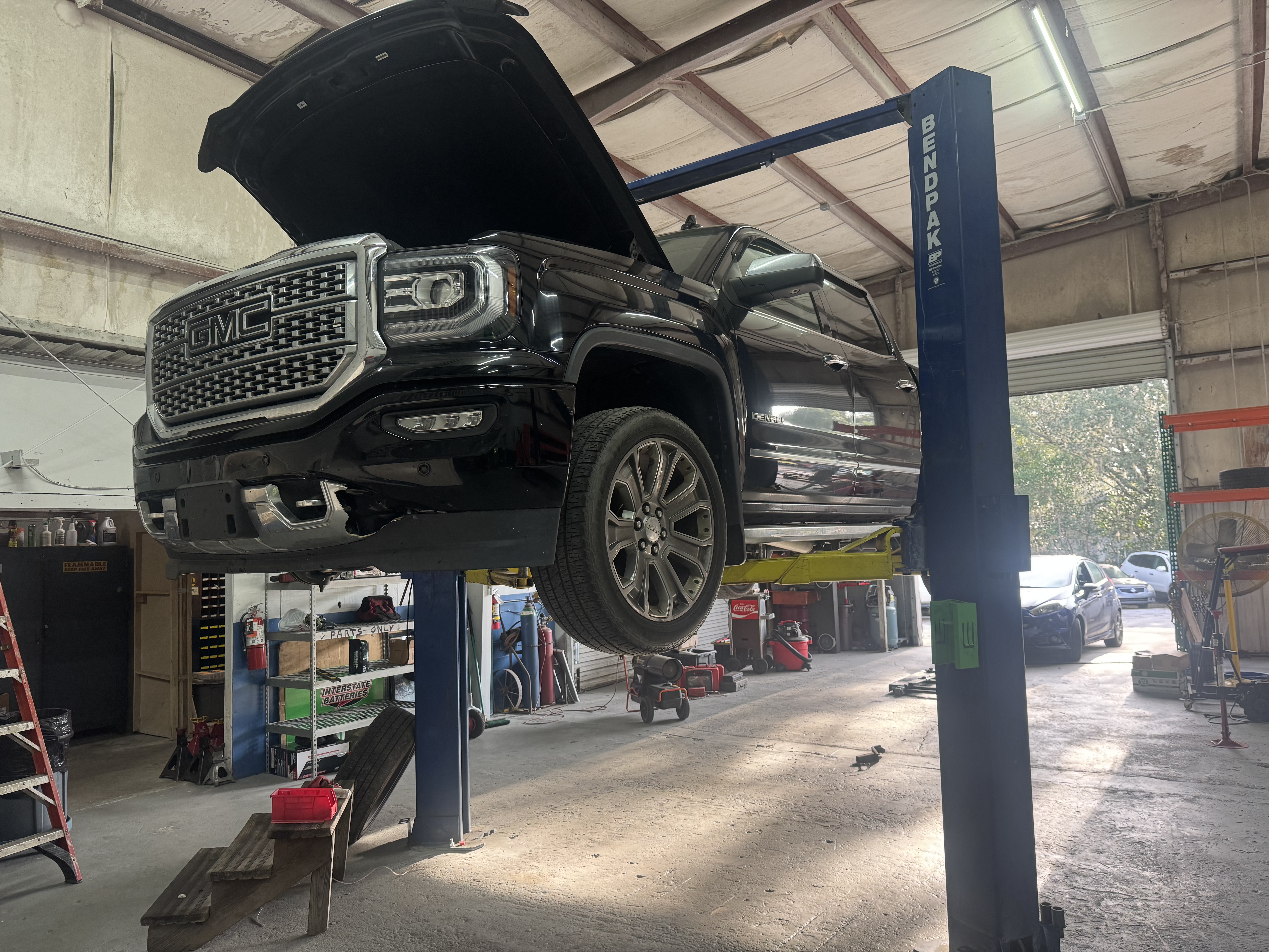 GMC Denali pickup truck elevated on a BendPak hydraulic lift inside Fox Automotive service bay during maintenance or repair work