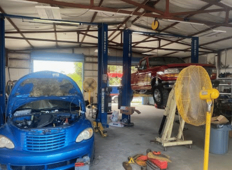 Multiple vehicles on lifts in busy auto repair shop showing diagnostic and repair work in progress