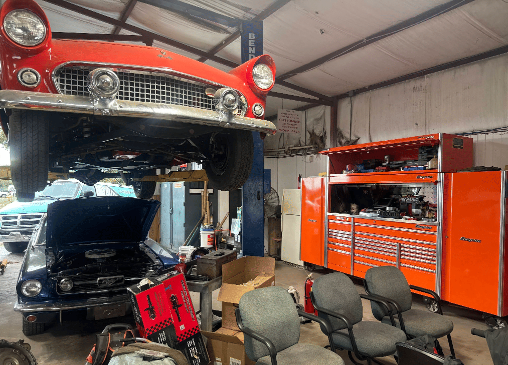 Classic red car elevated on lift in vintage automotive restoration shop
